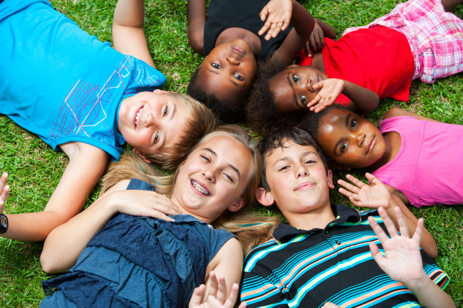 Diverse multiracial group of kids laying together joining heads.